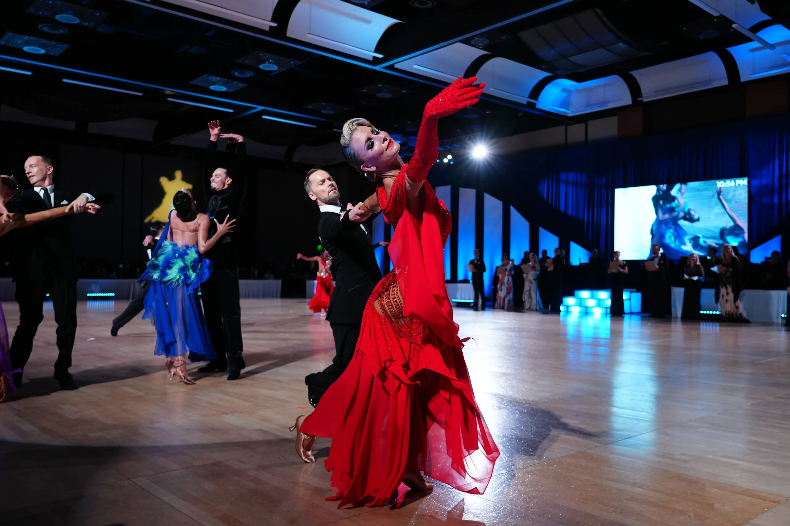 Jaimee sweeps into a deep oversway in a fanned red gown while Travis holds the line of the shape