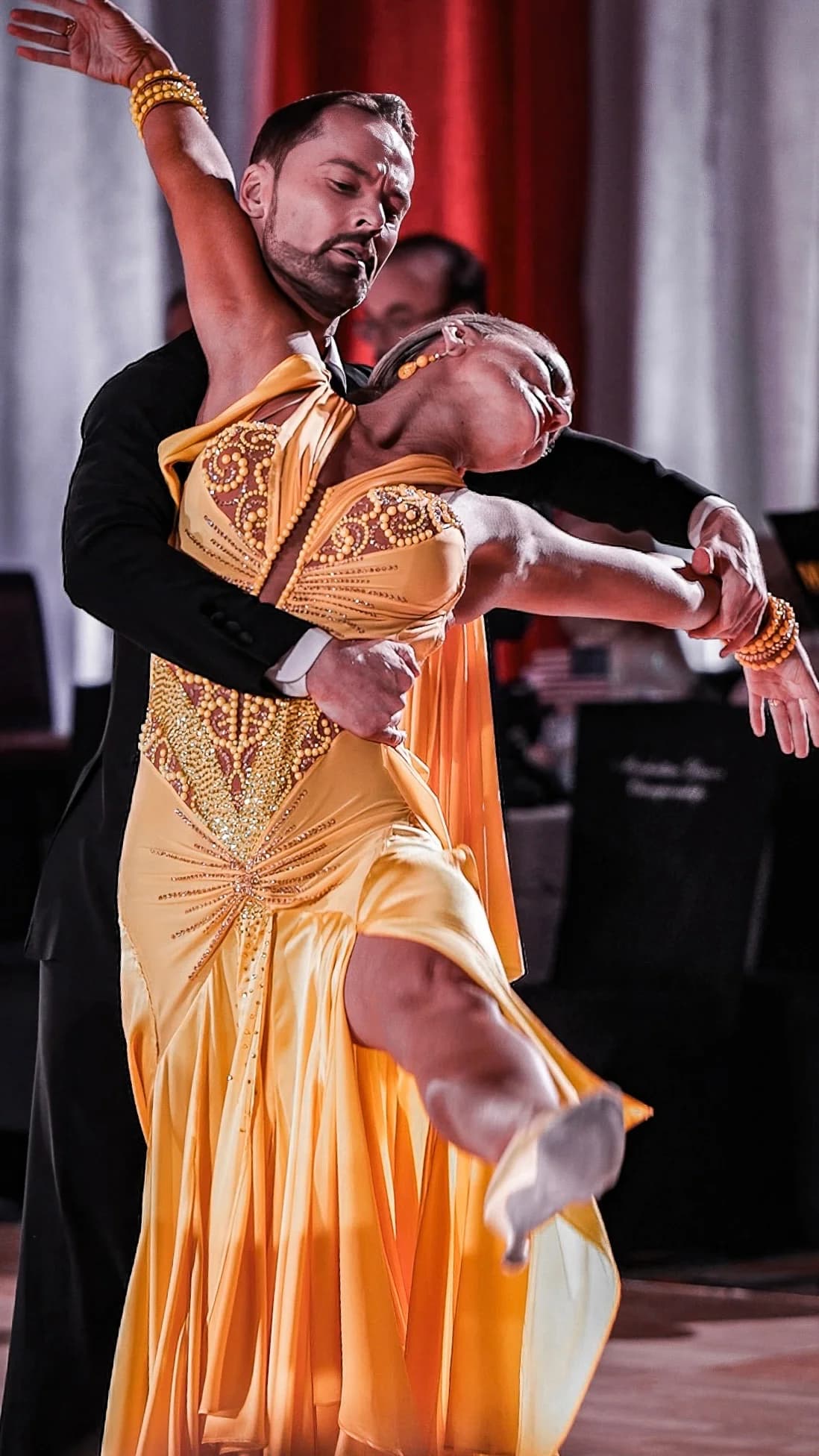Travis holds Jaimee through a deep arch in a golden gown, their faces almost touching