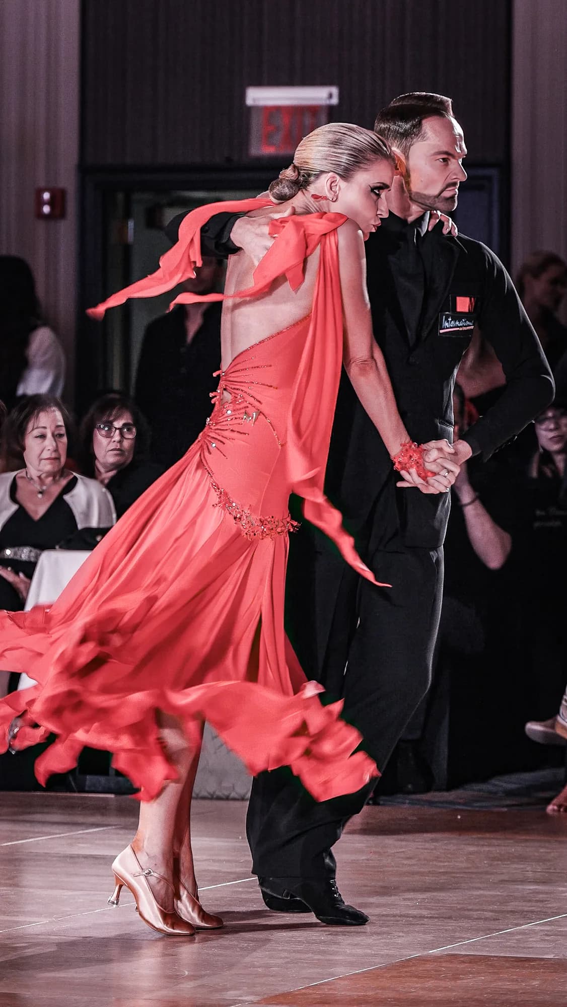 Jaimee's red dress swirls as she turns into Travis backstage