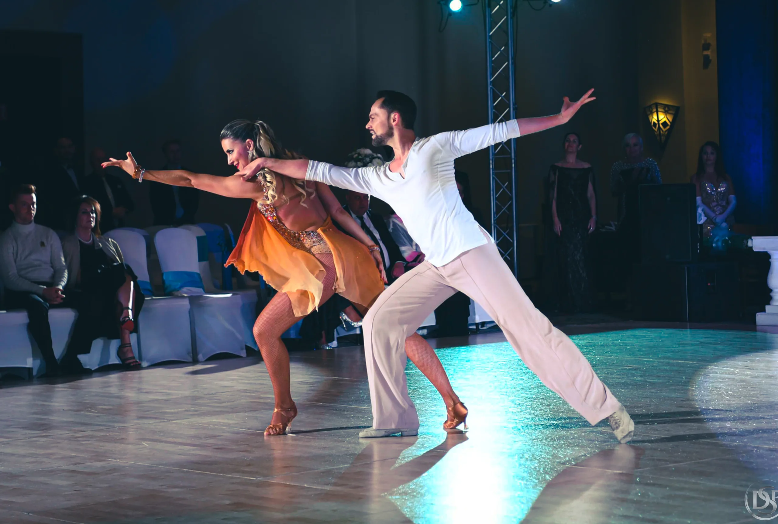 Travis kneels holding Jaimee close as her white dress spreads over the stage floor