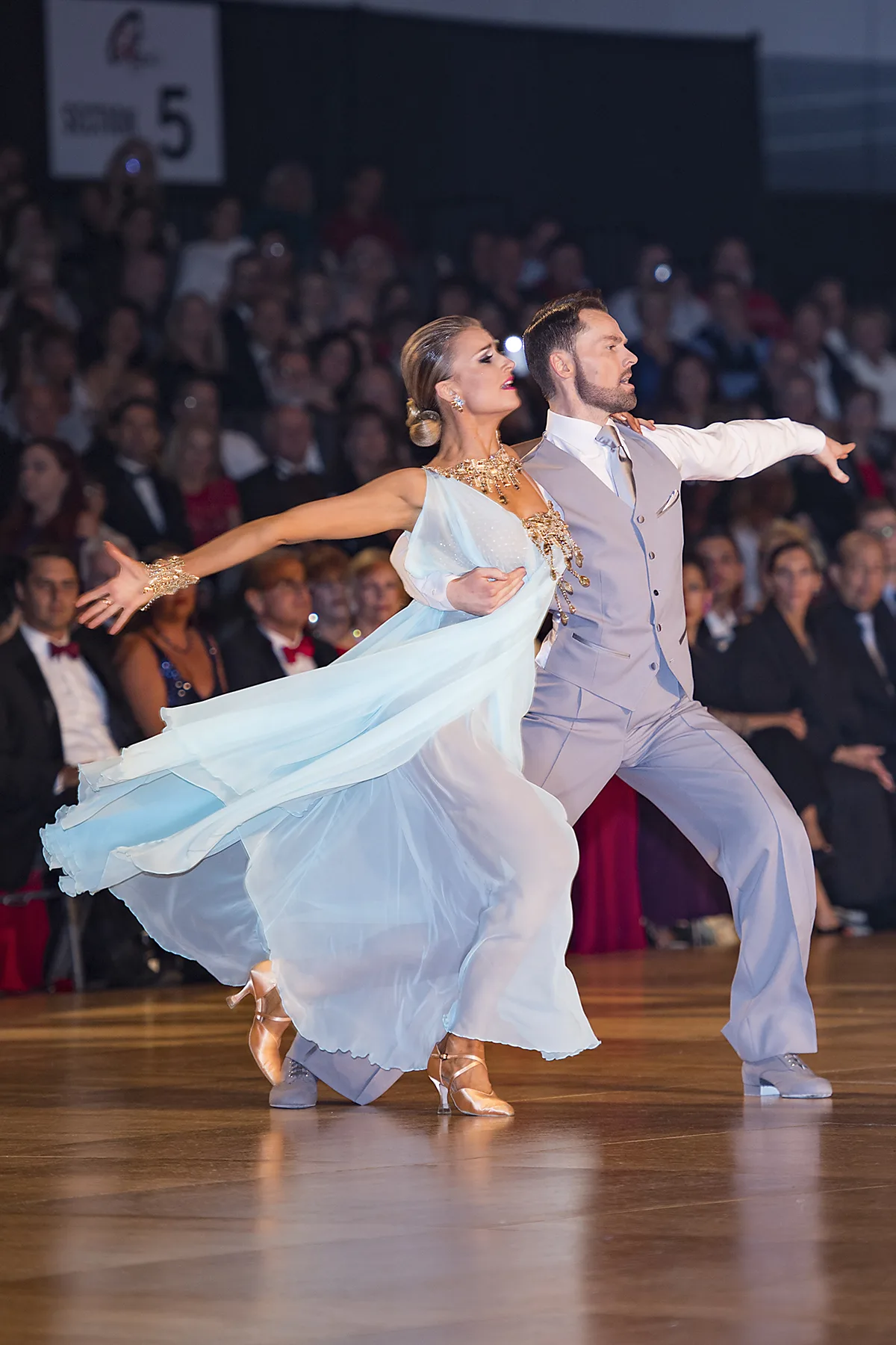 Jaimee's ice-blue gown streams as she and Travis stride together across the floor