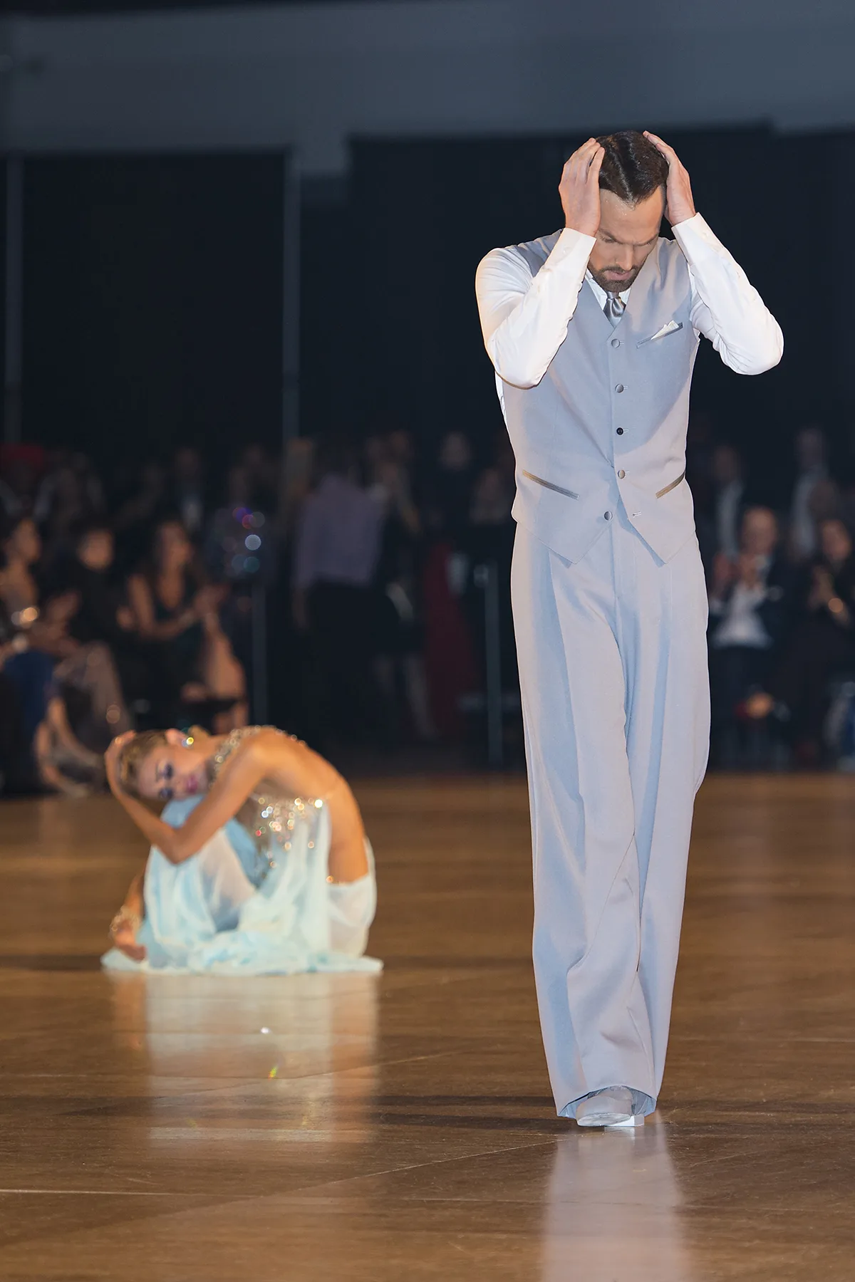 Travis stands with his hands on his head as Jaimee sinks to the floor behind him mid-story